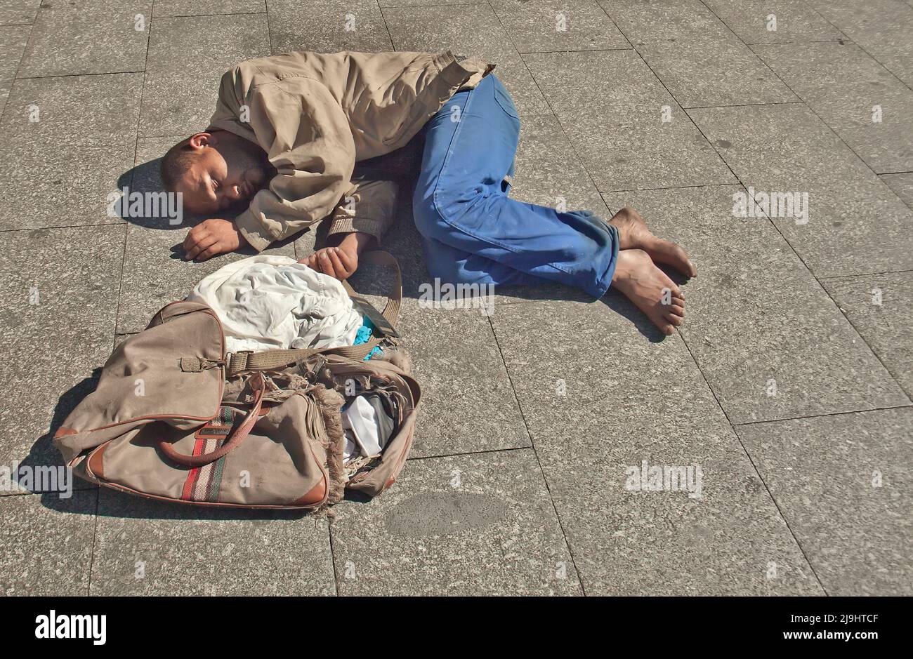 Barefoot man sleeping on ground in Sao Paulo, Brazil Stock Photo