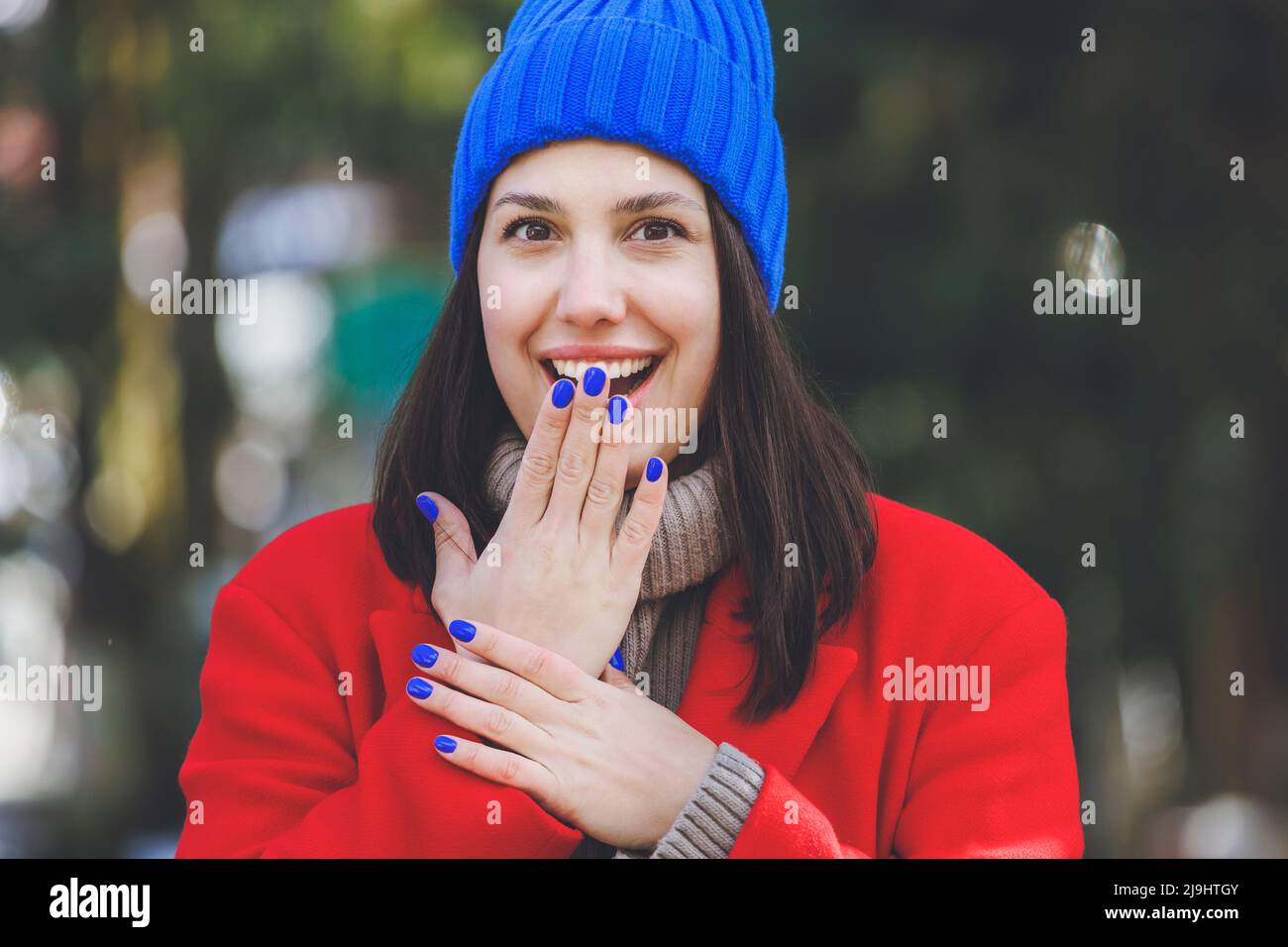 Surprise young woman with blue nail polish covering mouth with hand Stock Photo