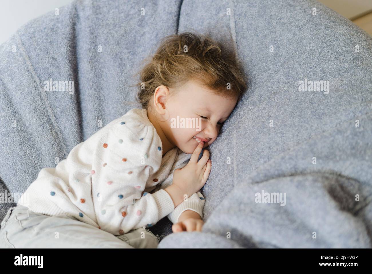 Smiling girl lying down on bean bag at home Stock Photo - Alamy