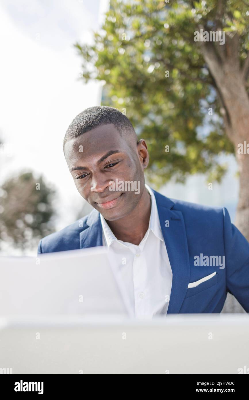 Smiling businessman analyzing document on sunny day Stock Photo