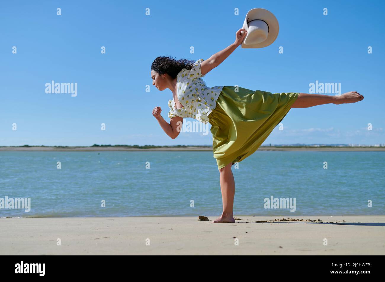 Young woman with hat in hand dancing at beach Stock Photo