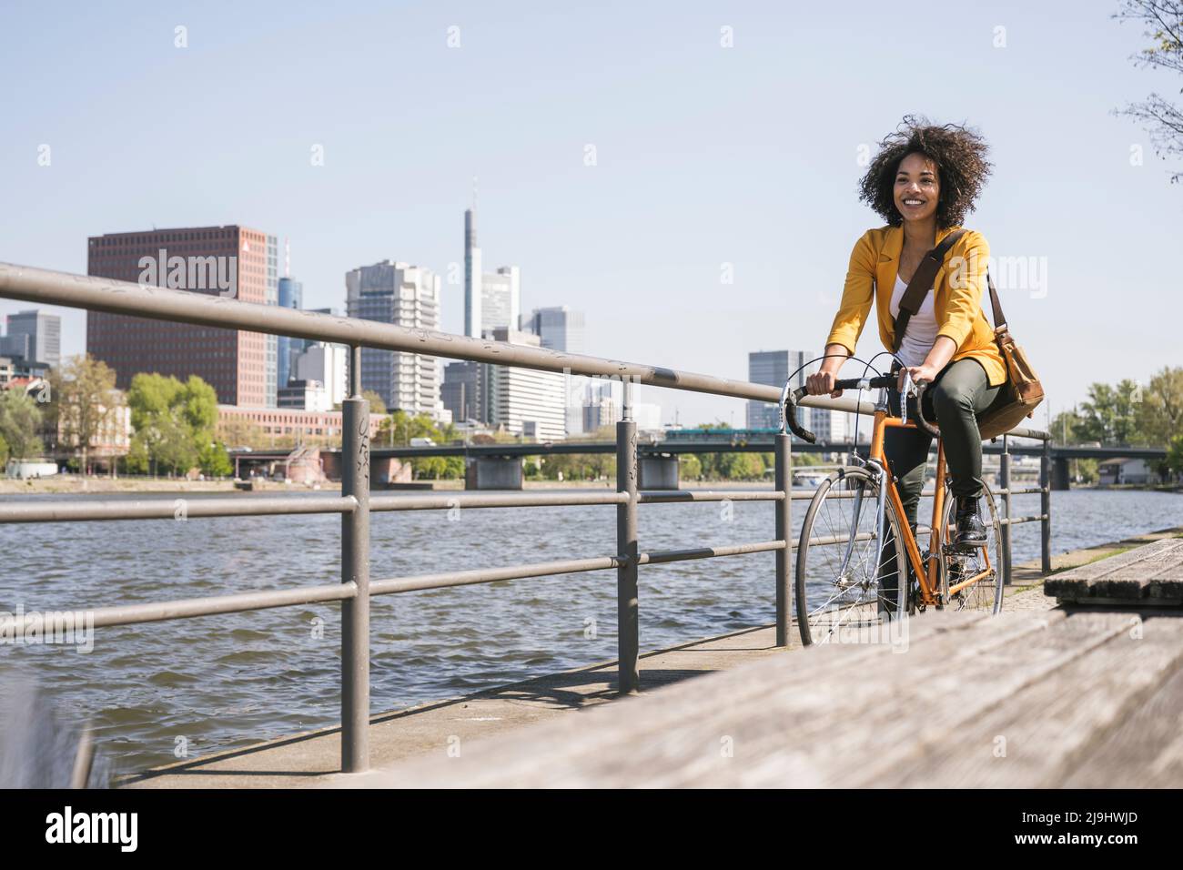 Commuter cycling by River Main on sunny day Stock Photo