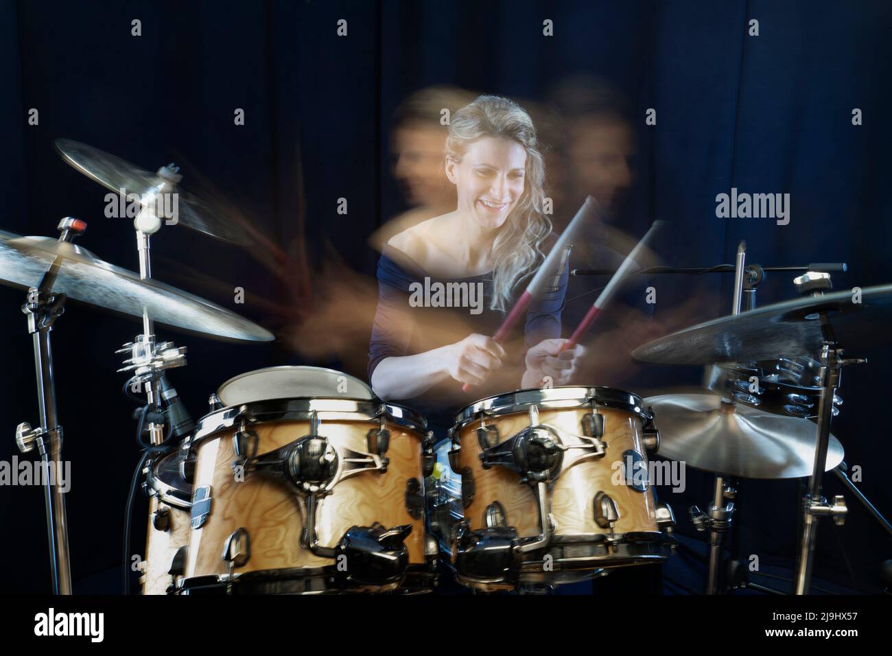 Happy drummer playing drum kit against black background Stock Photo