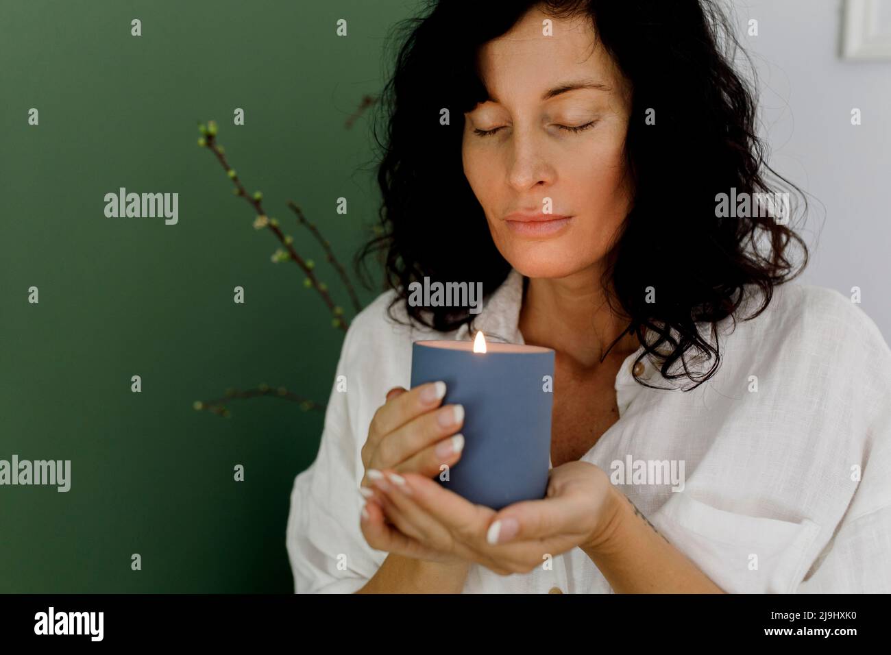 Woman with eyes closed holding candle at home Stock Photo