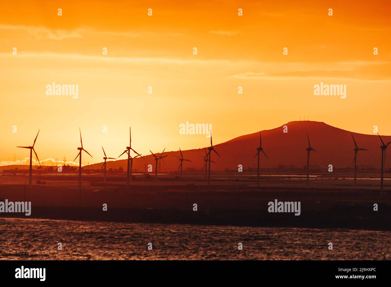 Silhouette wind turbines in front of mountain at sunset Stock Photo - Alamy