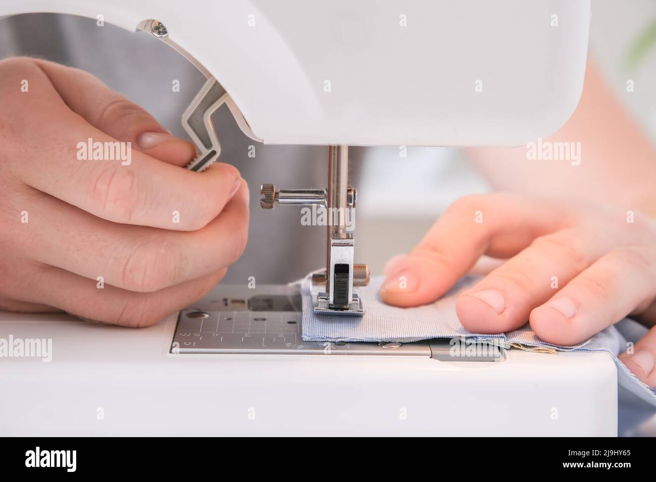 A man sews clothes on a sewing machine. Hobbies, needlework, creativity. Stock Photo
