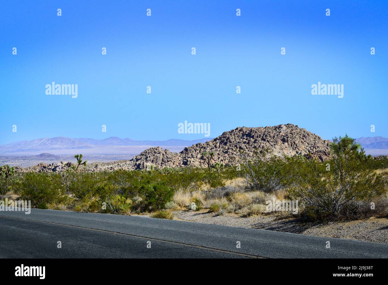 Joshua Tree National Park, in the Mojave desert, with a highway view of the expanding Coachcella Valley and rock formations with desert landscape, CA Stock Photo