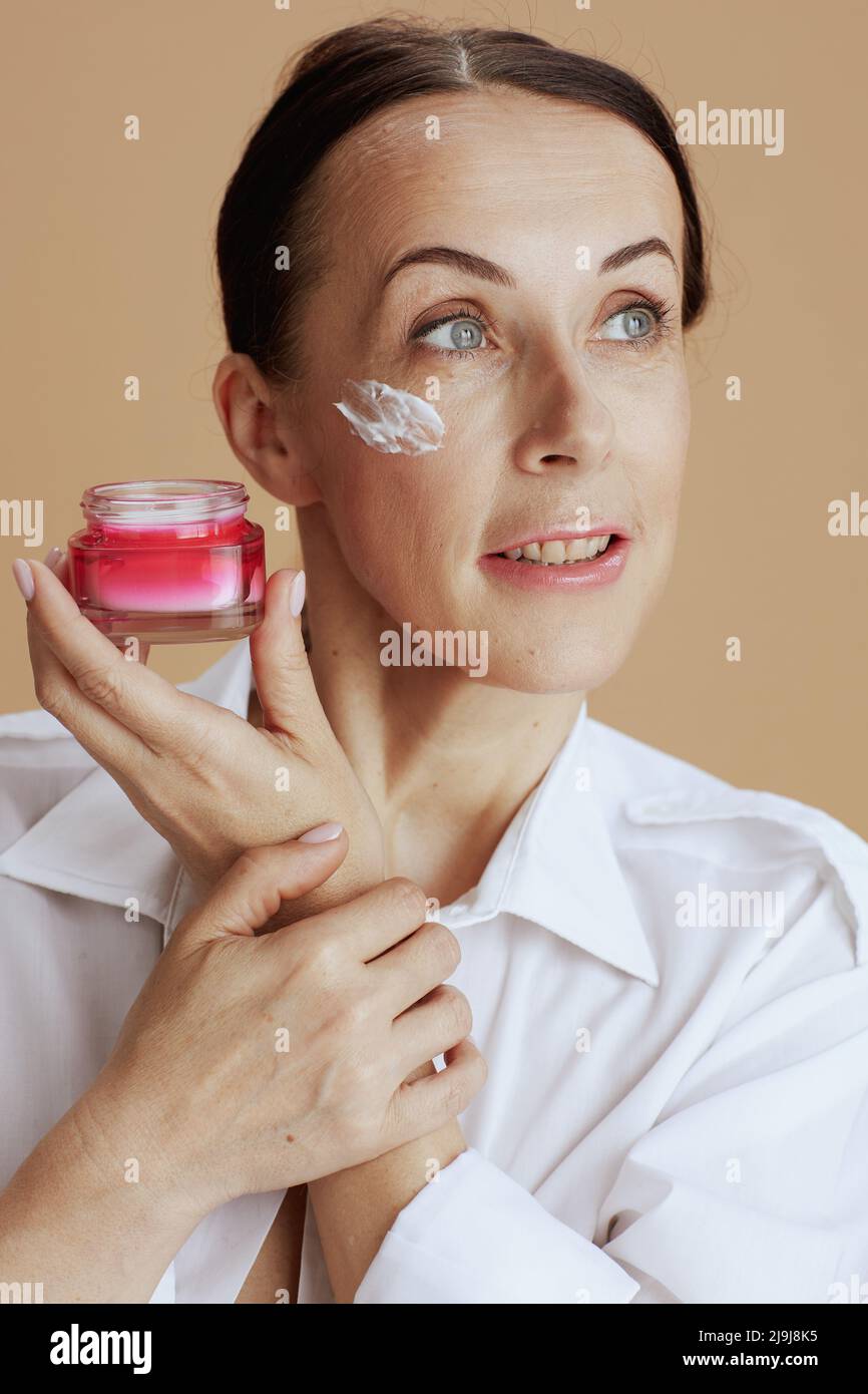 Modern Woman With Facial Cream Jar In White Shirt Isolated On Beige