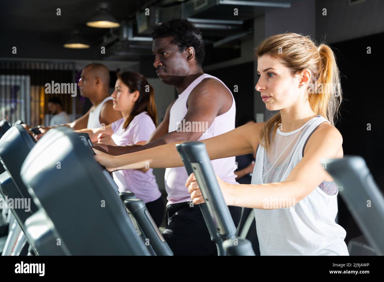 People having running elliptical trainer class in club Stock Photo Alamy