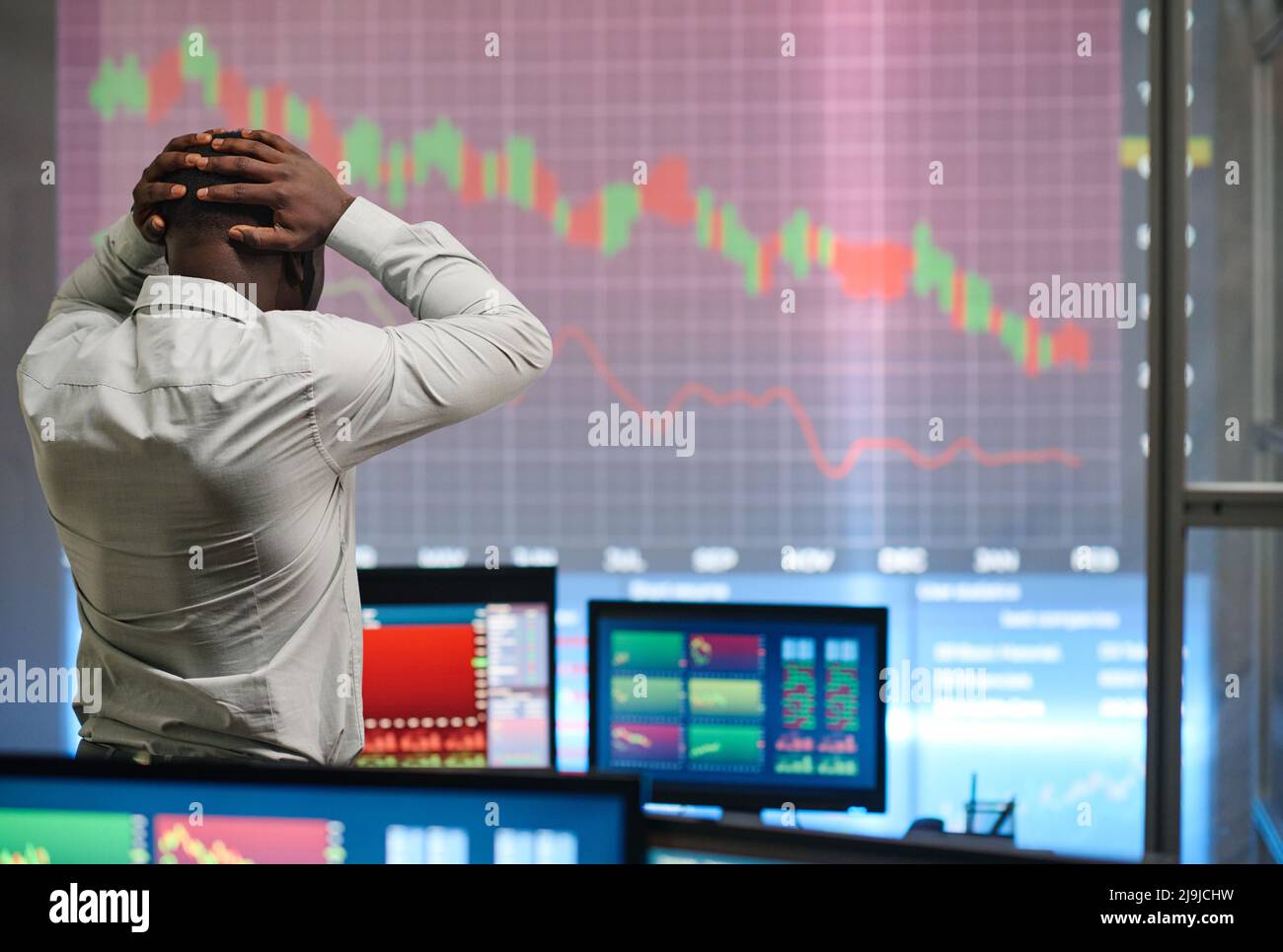 Unrecognizable Black man wearing white shirt working in stock trading company looking at graph decreasing and feeling disappointment Stock Photo