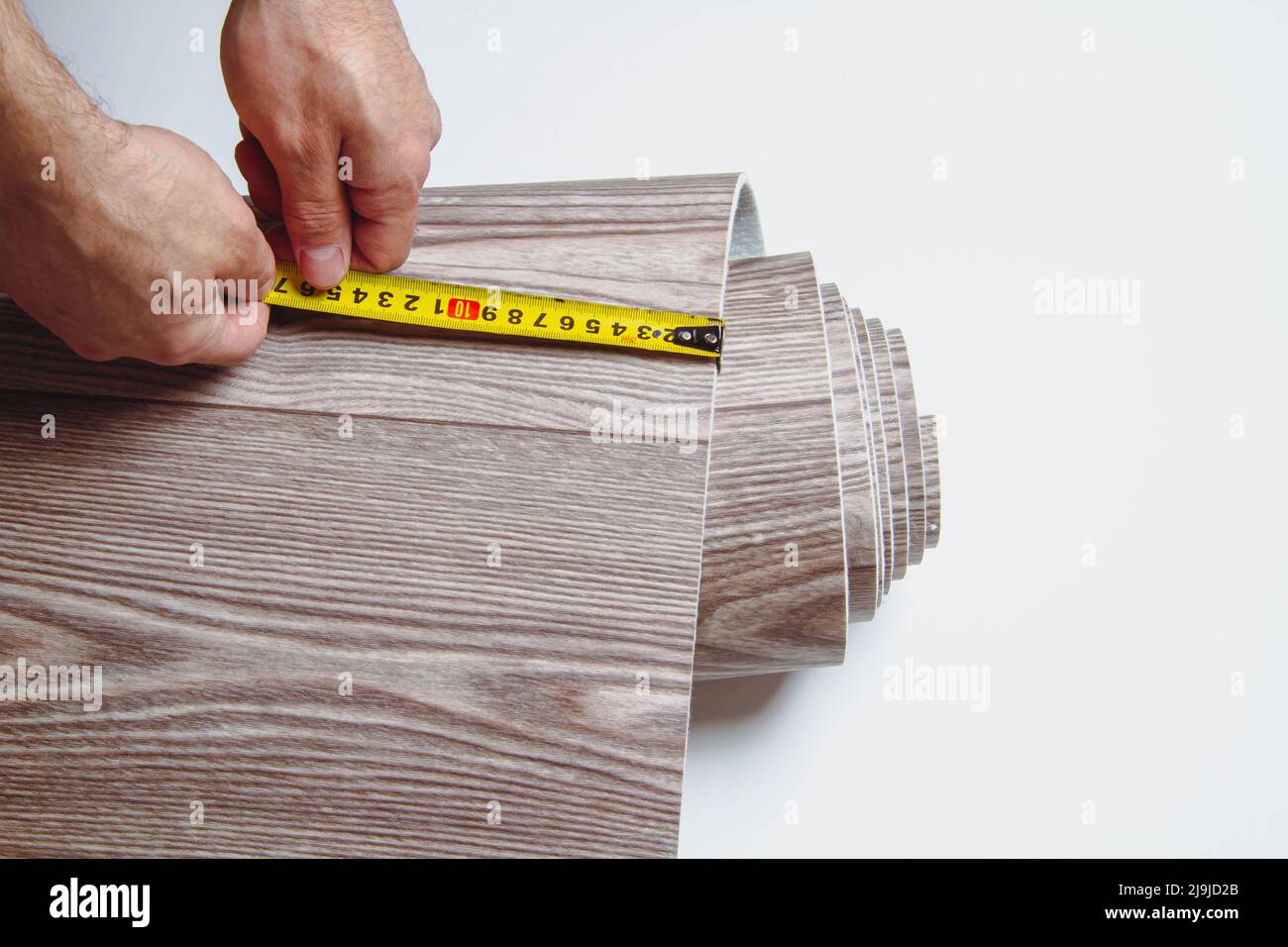 Measurement of linoleum on a cut. Man cuts linoleum. Tape measure and a man's hand with a piece
