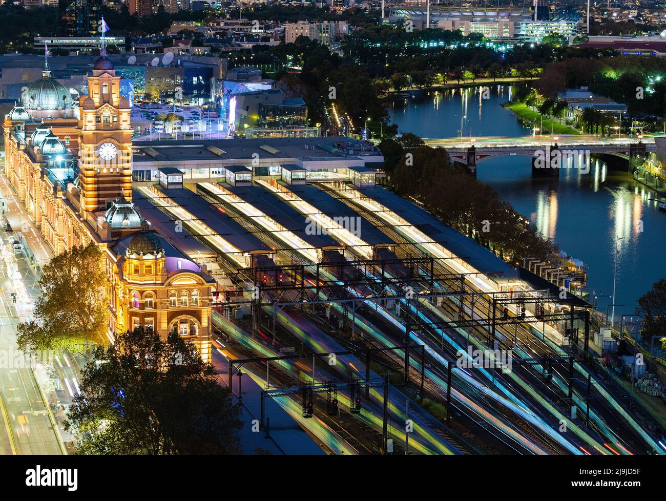 Melbourne, Australia - May 2, 2022: Flinders Street Railway Station in Melbourne CBD at night, multiple photos stacked to create train light trails Stock Photo