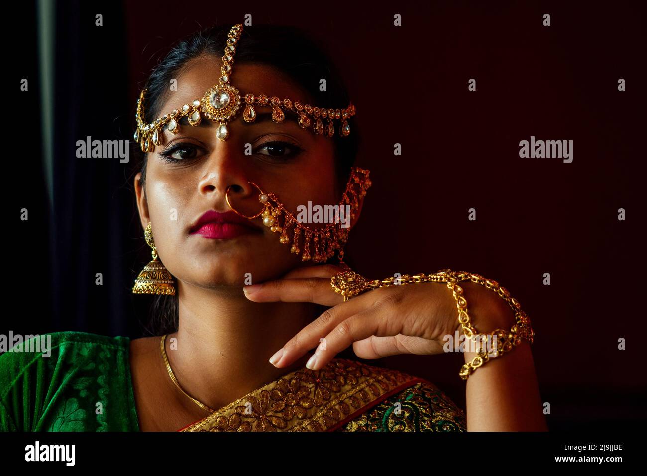 Woman lighting diyas with nuth nath nose piercing and the golden teak with traditionak fashion sari Stock Photo