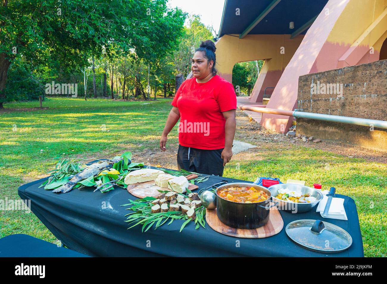 Young Aboriginal woman standing in front of a cooked meal during cooking classes at the Taste of Kakadu Festival, Cooinda, Kakadu National Park, North Stock Photo
