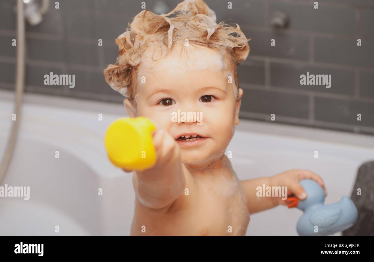 Happy baby taking a bath playing with foam bubbles. Little child in a