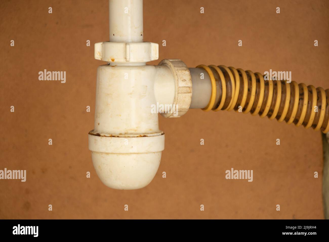 The siphon on the kitchen sink in the closet is dirty and old, the kitchen pipe is under the sink Stock Photo