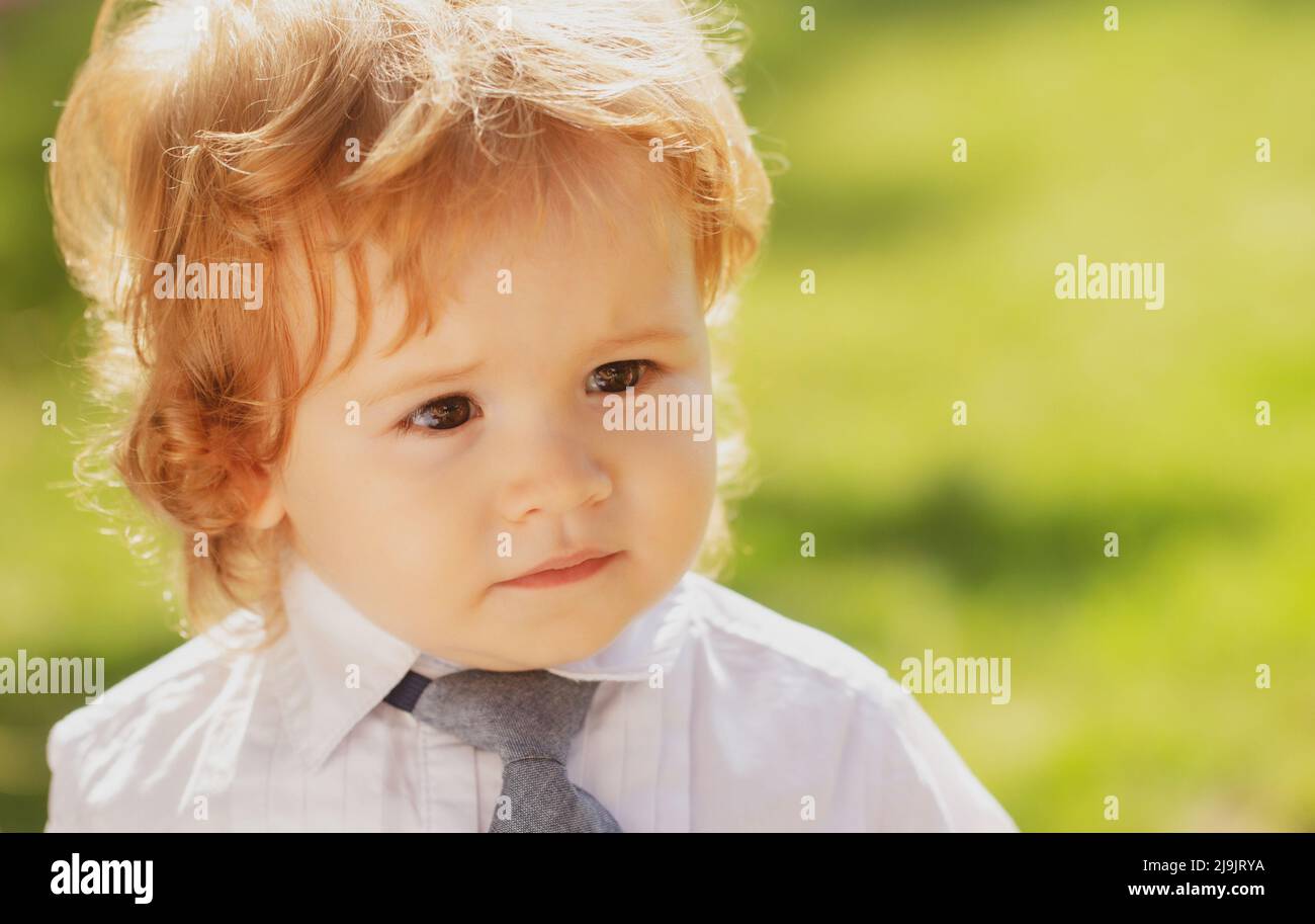 Funny baby child face. Outdoor portrait of cute little boy in suit and