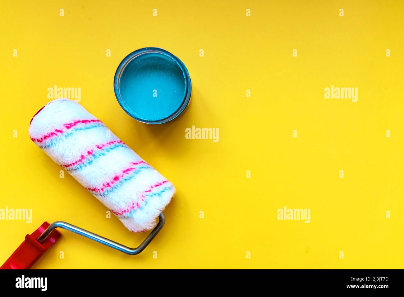 Paint roller for painting and priming on yellow background with blue