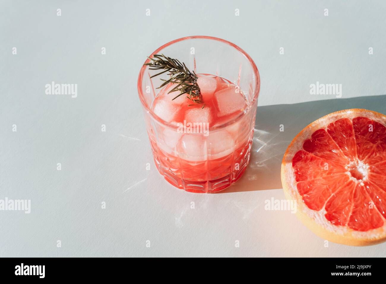 Fresh red grapefruit juice with ingredients in sunlight. Top view, copy space. Stock Photo