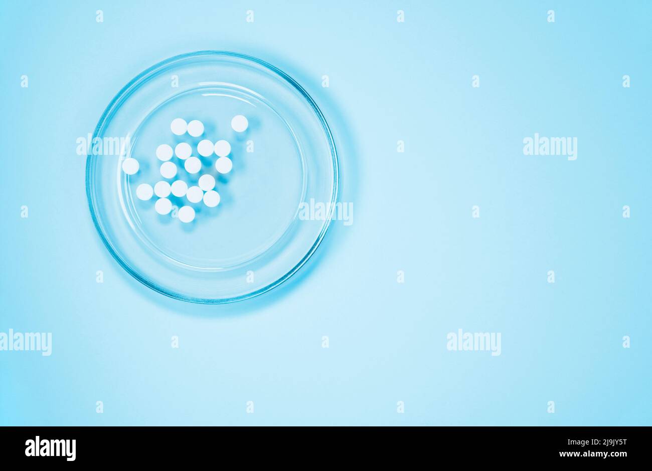 White pills on glass tray on blue background , hearth care  and medicine Stock Photo