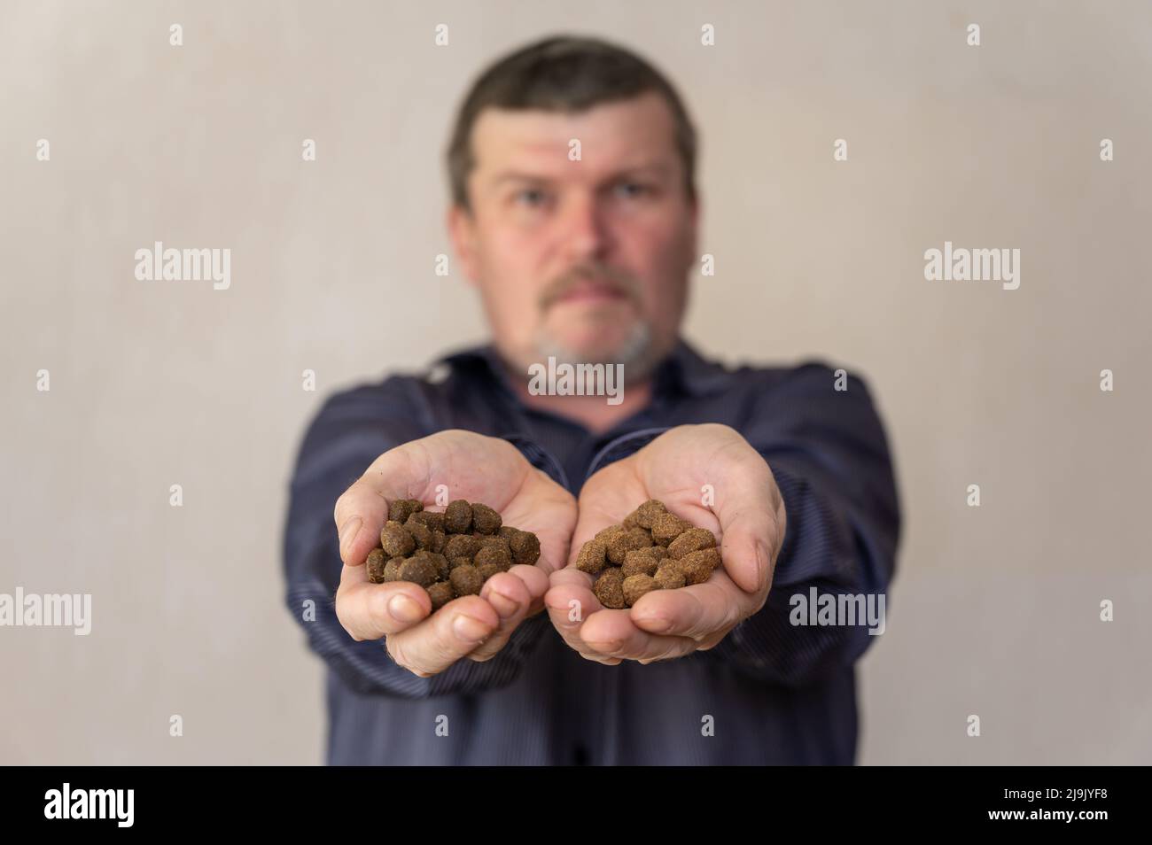 Man holds out his palms with pet food for the camera. Close-up of the ...