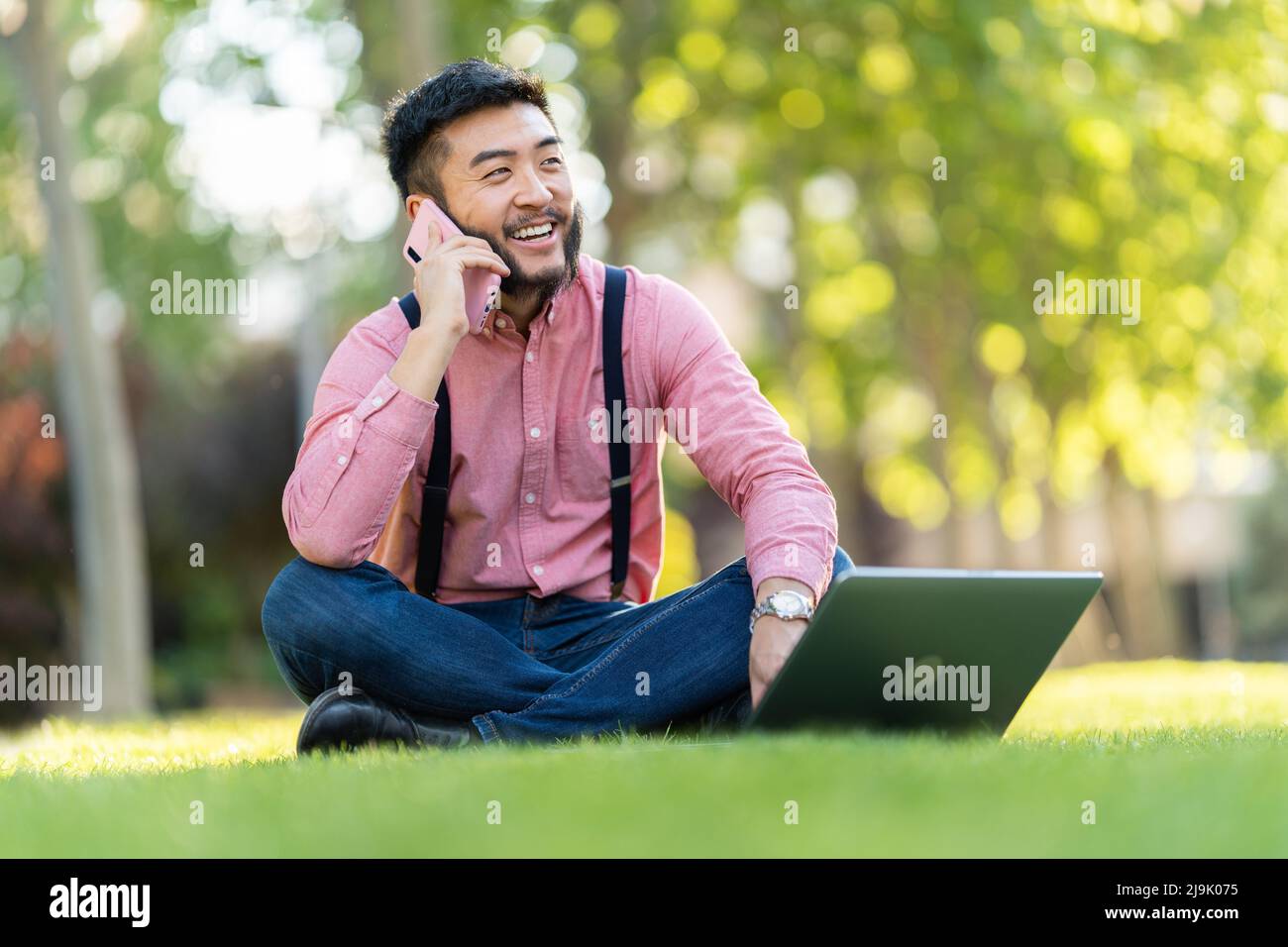 Man talking on a mobile while working on a laptop Stock Photo