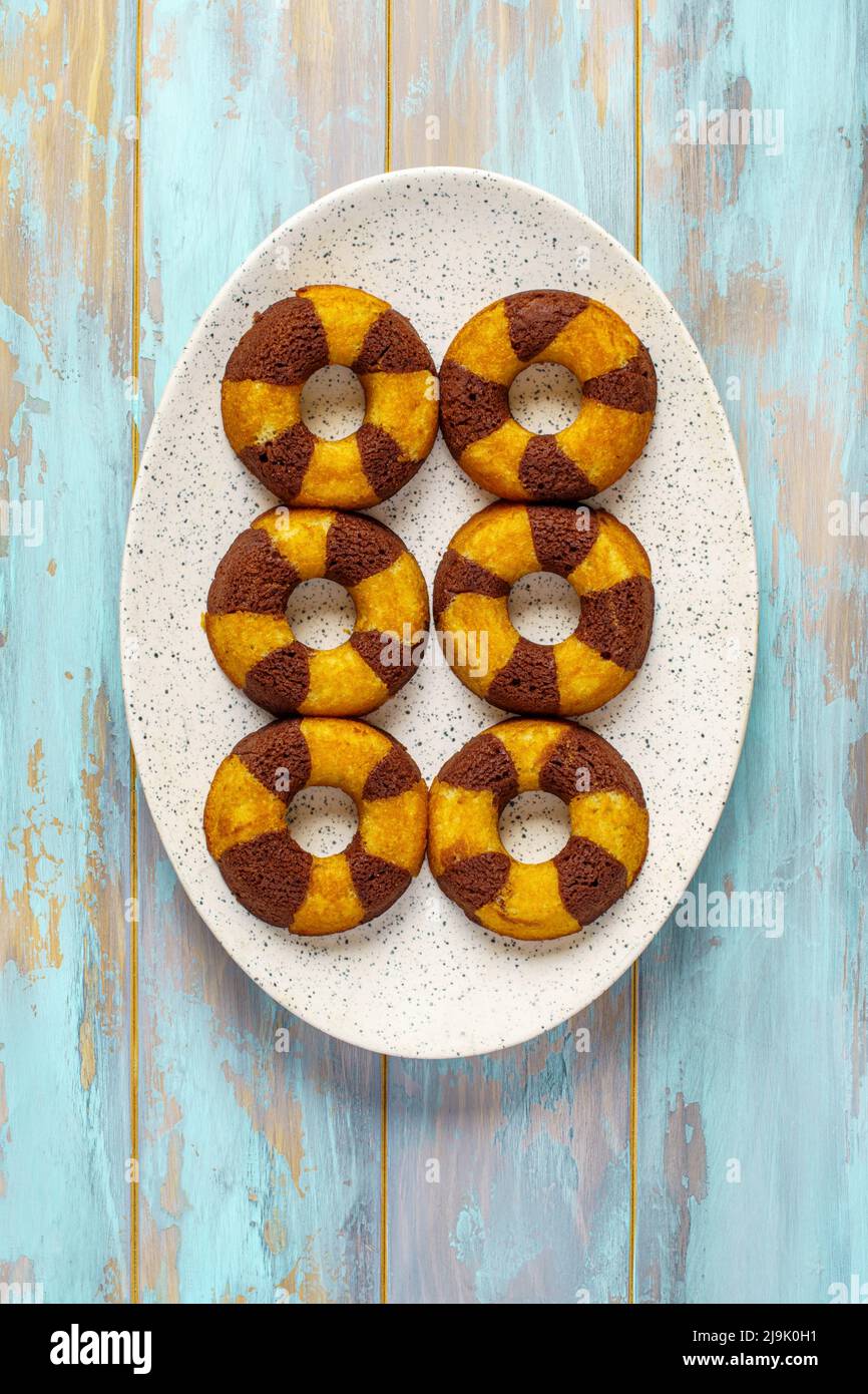 Sweet cake rings with chocolate filling on blue wooden background top view Stock Photo