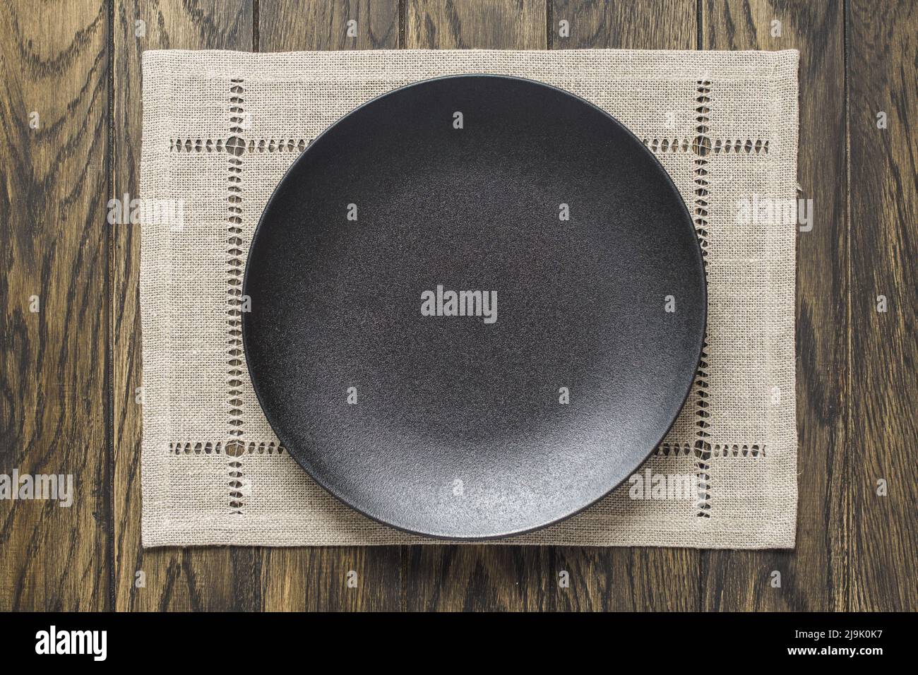 Empty black plate and gray napkin on oak wooden table. Top view, with copy space Stock Photo