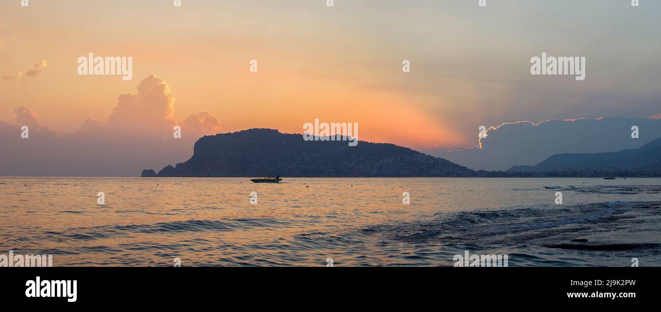 Panorama of Alanya peninsula at dusk. Silhouette on the background of the evening sky with clouds Stock Photo