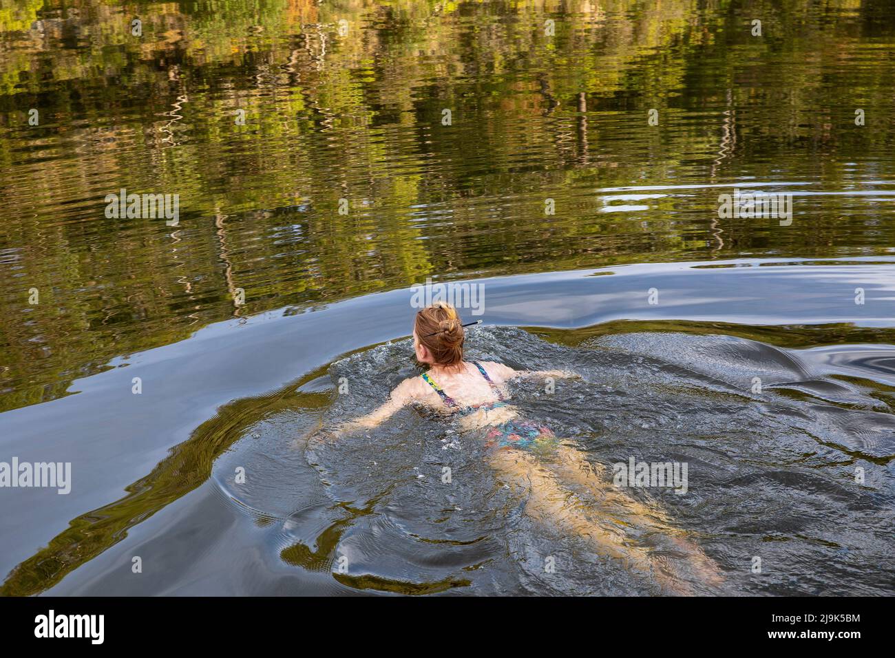 Carefree woman swimming in tranquil summer river Stock Photo