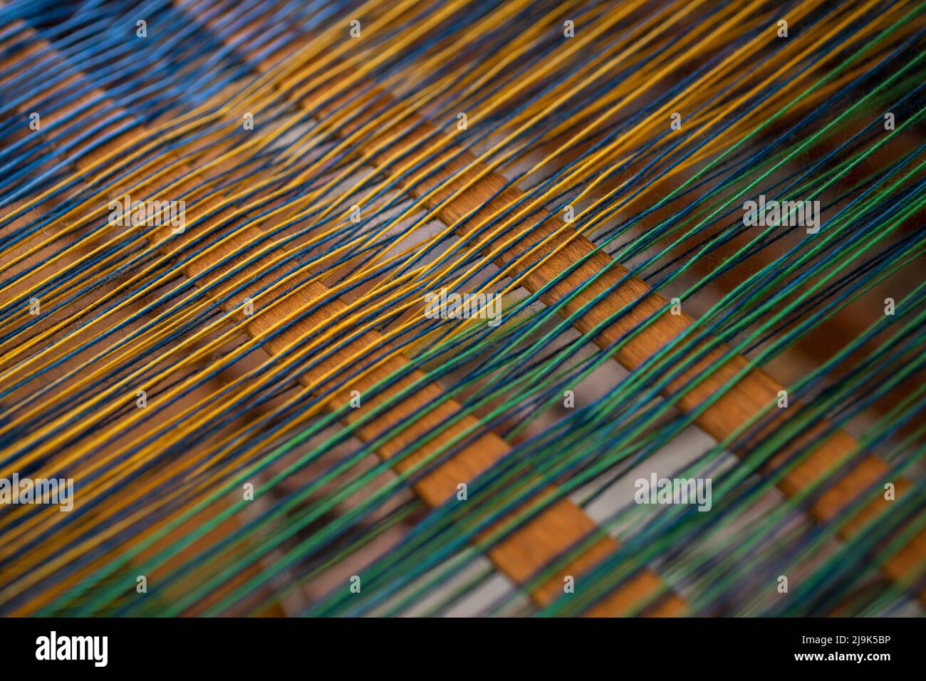 Close up green and yellow thread on loom Stock Photo