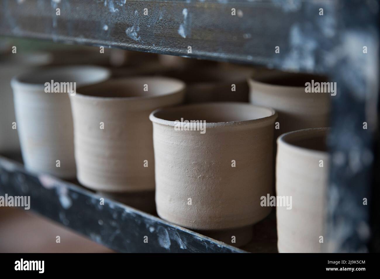 Close up thrown clay cups drying in a row Stock Photo