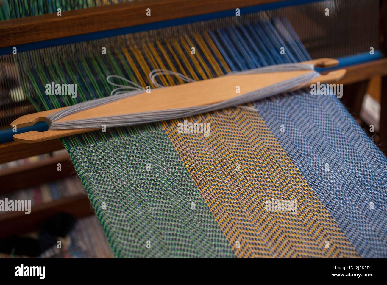 Blue, green and orange thread forming pattern on loom Stock Photo