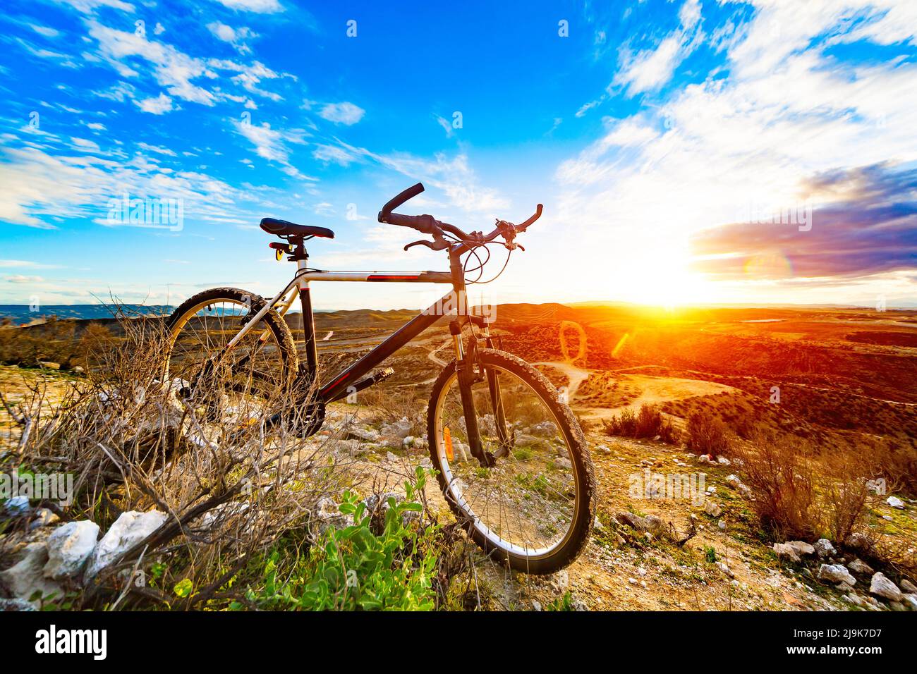 mountain bikes leaned on a rock next to a beautiful down hill trail and sunset landscape Stock Photo