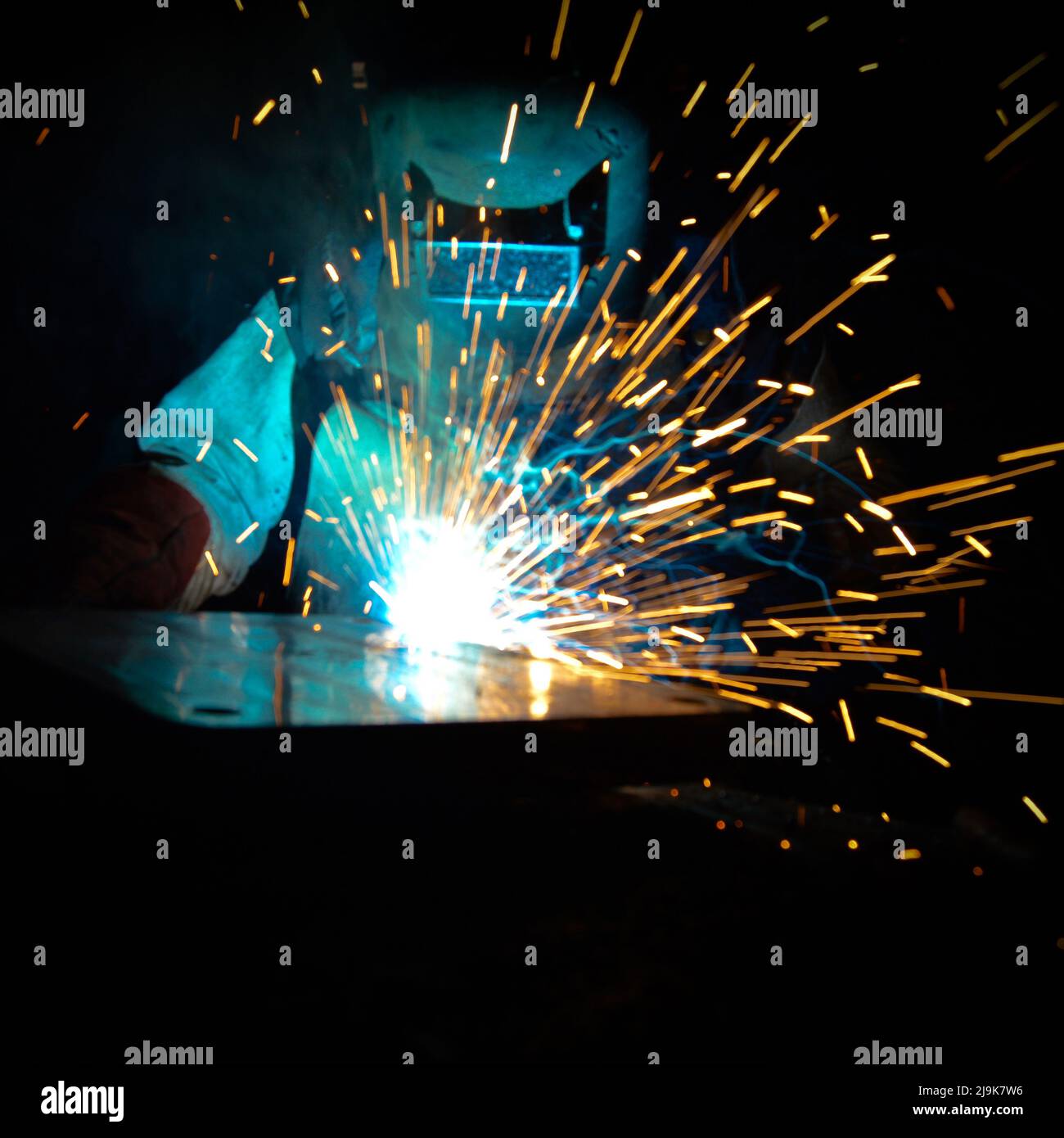Welder uses torch to make sparks during manufacture of metal equipment, professional welding