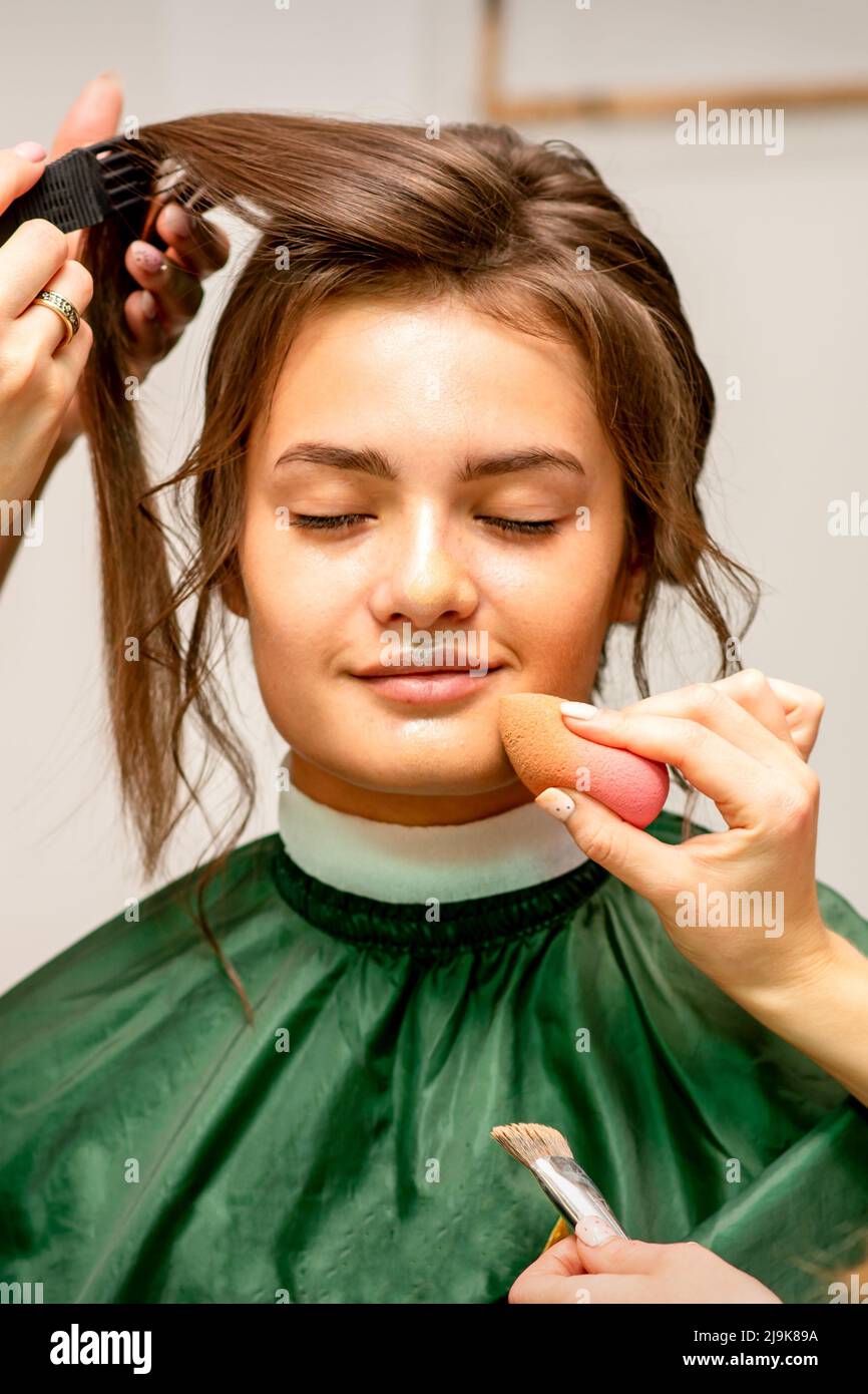 Makeup artist and hairdresser prepare the bride making hairstyle and