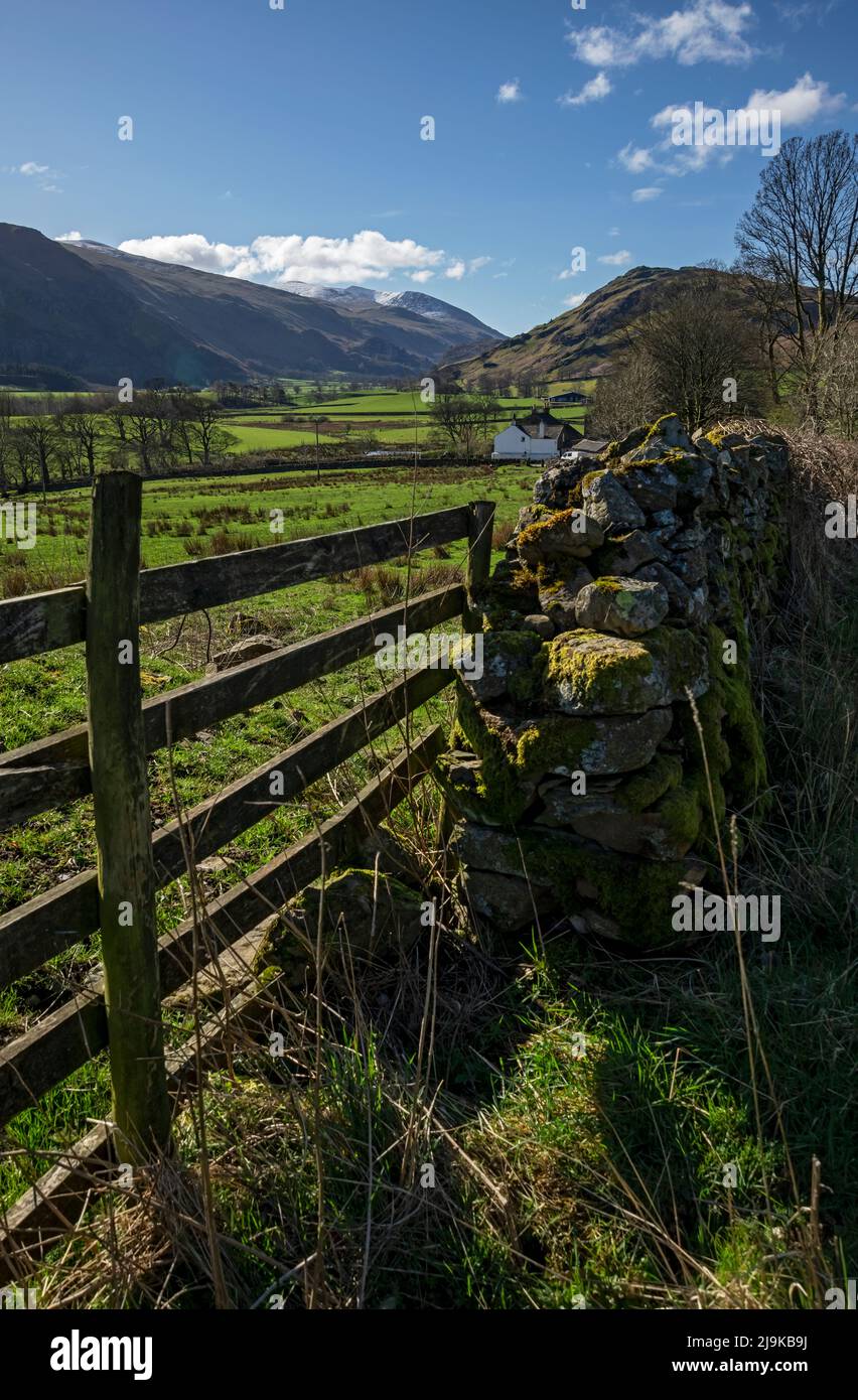 View along St John's in the Vale farmland towards snow on Helvellyn mountain range spring late winter Lake District National Park Cumbria England UK Stock Photo