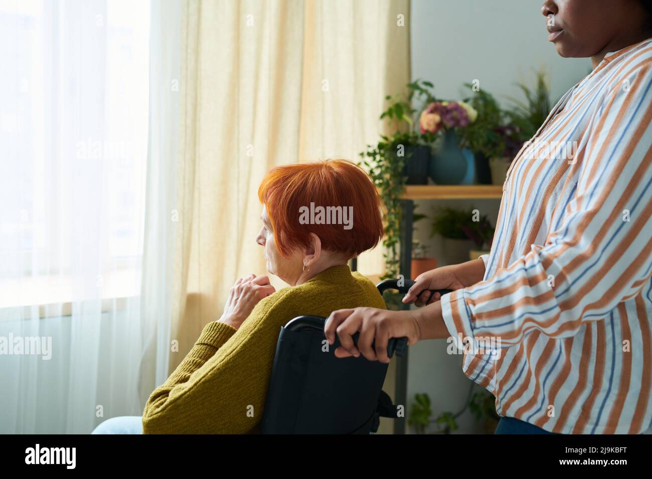 African young woman caring about elderly woman with disability at home Stock Photo