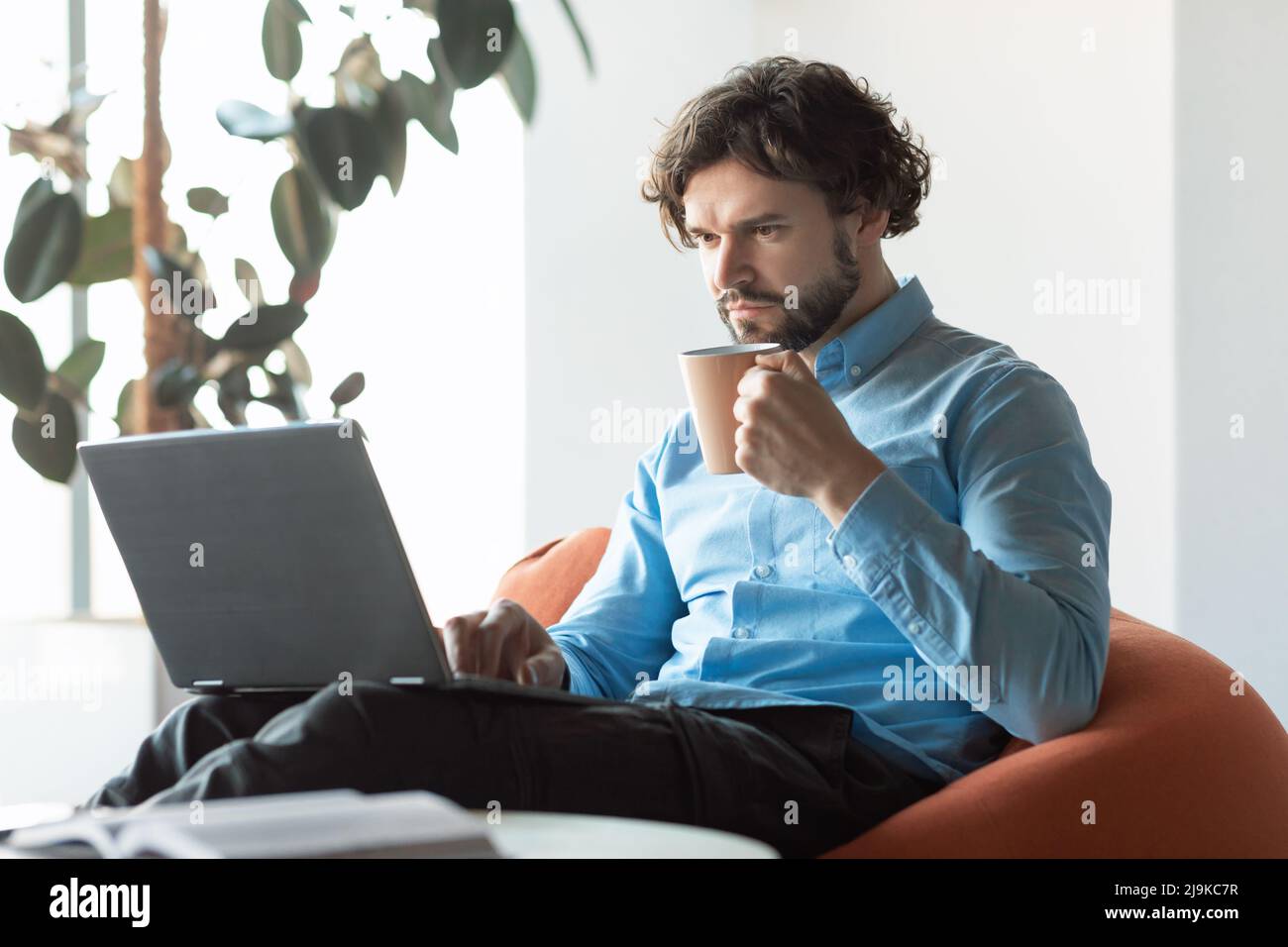 Business man using pc sitting on chair drinking coffee Stock Photo