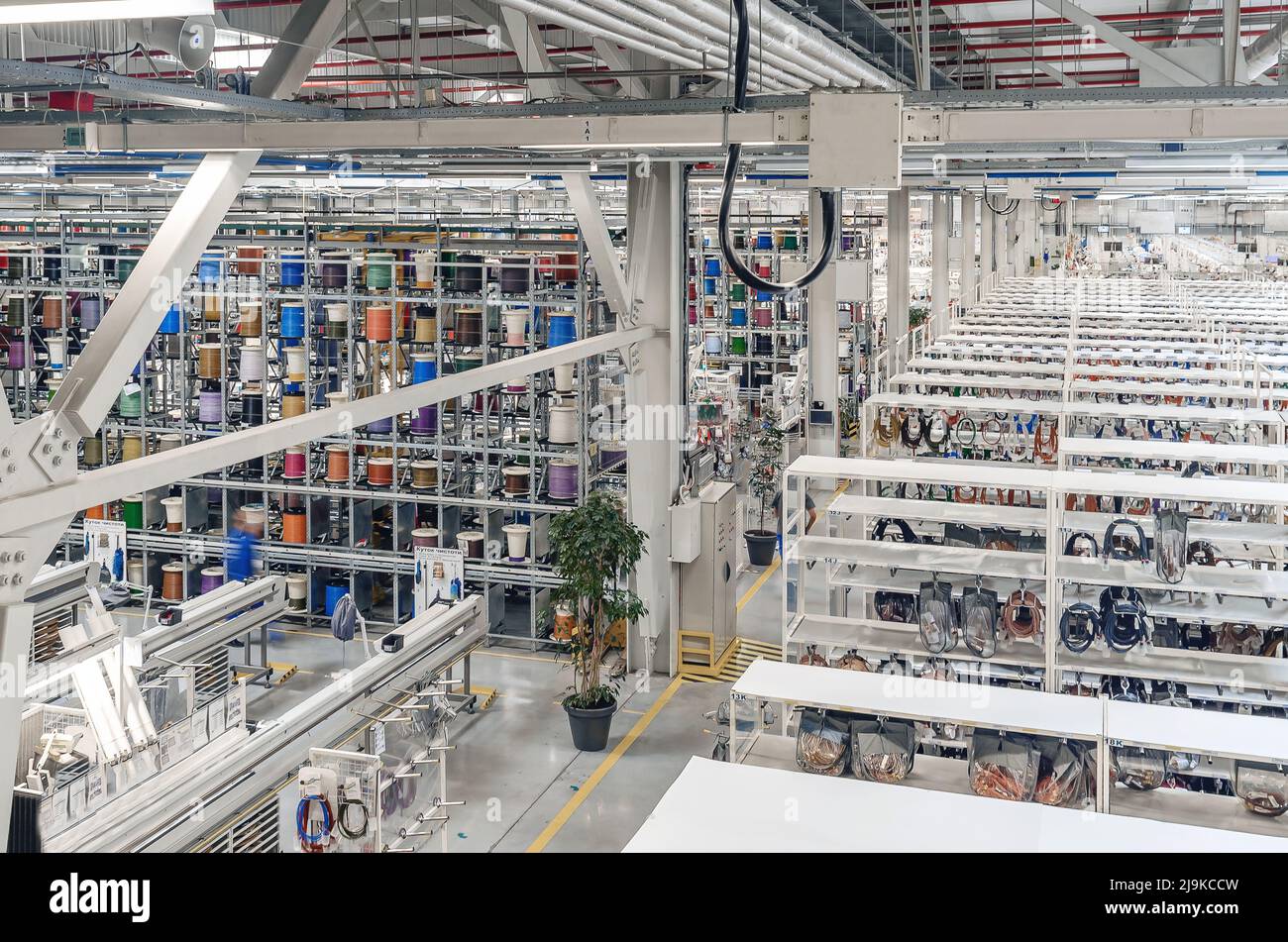 Interior of modern warehouse with coils of colored cable on metal shelves. Car wiring plant. Panoramic view. Stock Photo