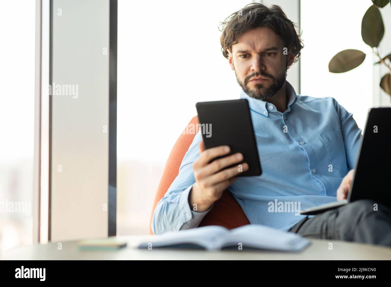 Portrait of focused man using digital tablet and pc Stock Photo