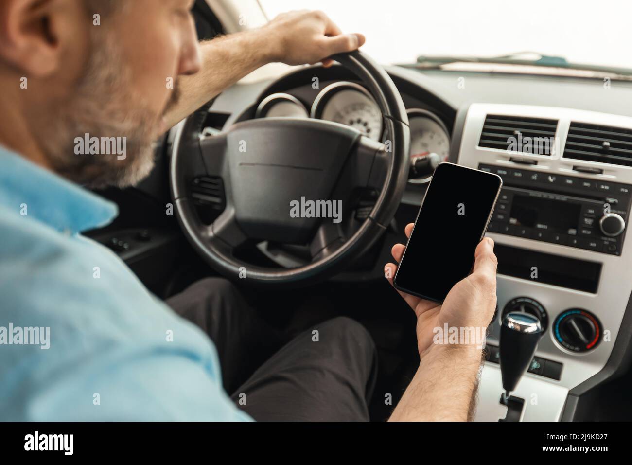 Driver man using smartphone with empty screen driving car Stock Photo