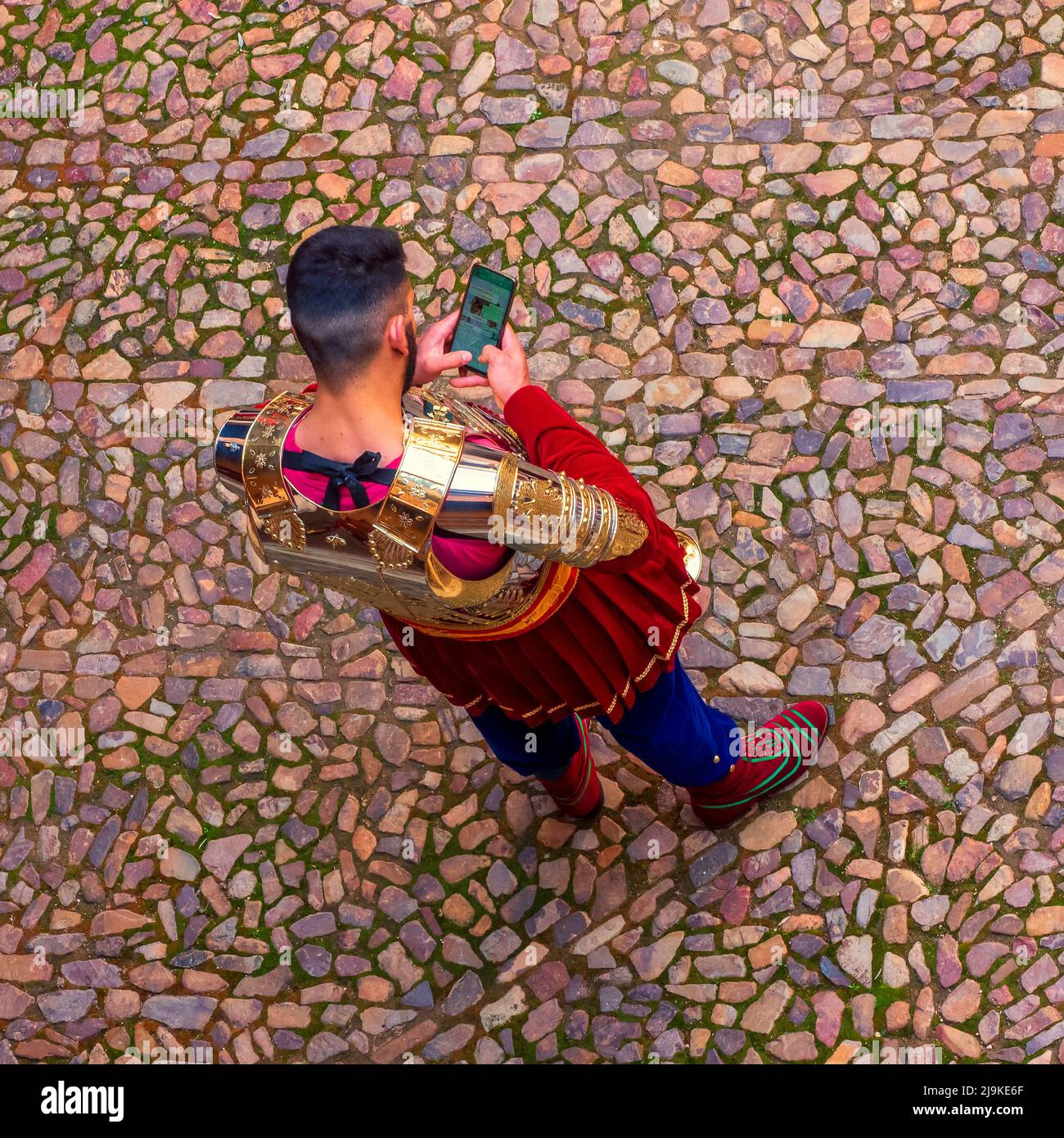 A member of the Roman Company of Almagro, waiting for the moment to parade through the streets during the Holy Week, looking at his mobile phone. Stock Photo