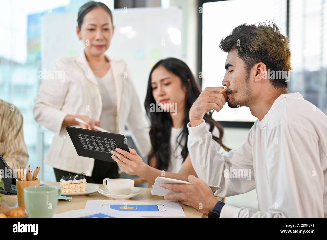 A group of graphic designers and web developers are in the meeting with aged senior female executive manager. Stock Photo