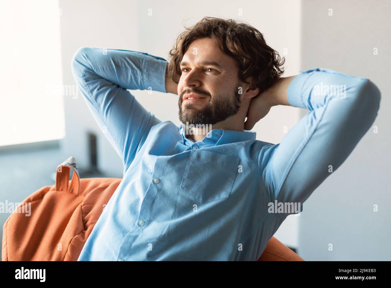 Smiling middle aged man sitting on beanbag and thinking Stock Photo - Alamy
