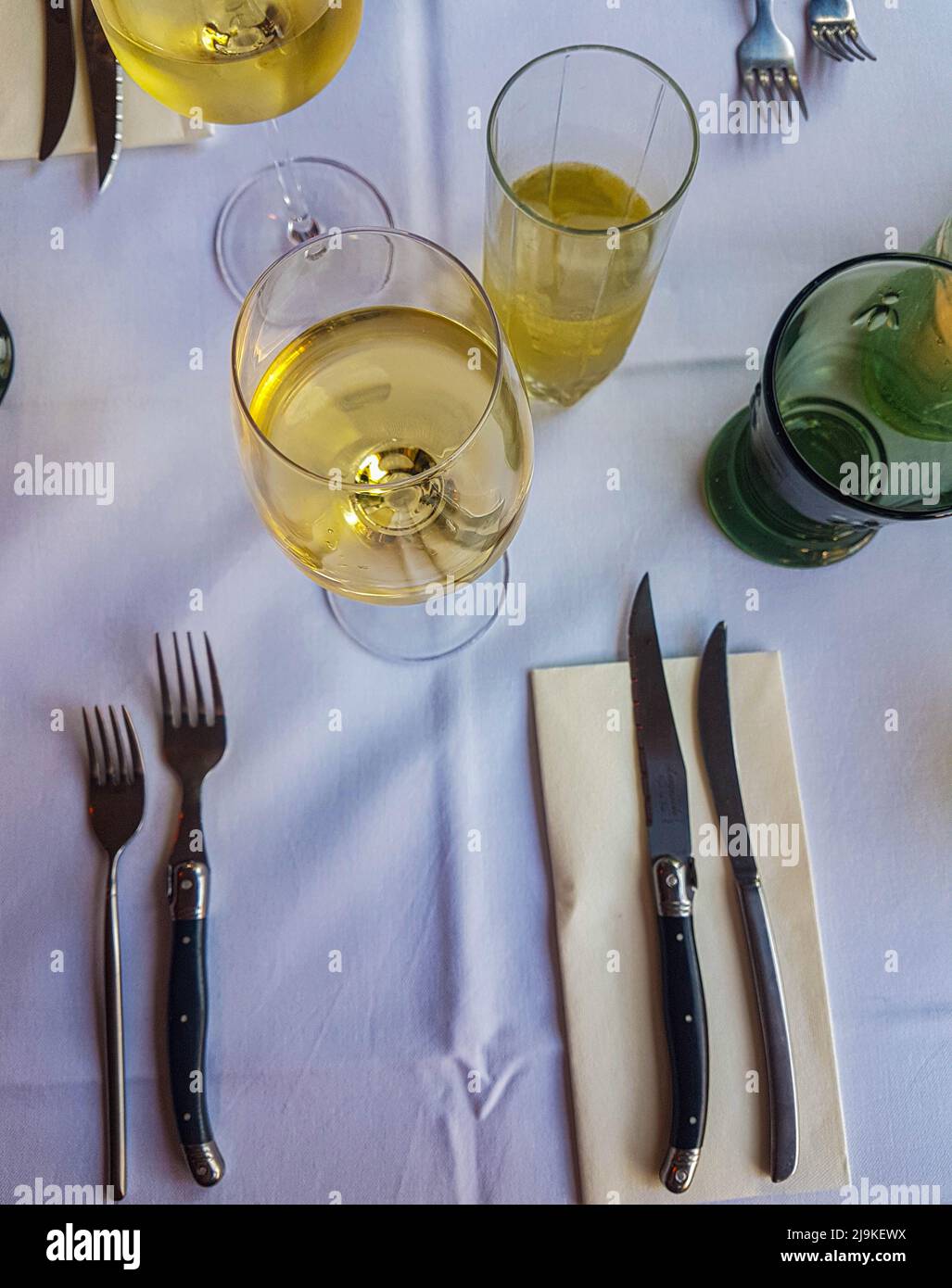 Bistro restaurant table with luxurious knives and forks and a delicious white wine in the middle Stock Photo