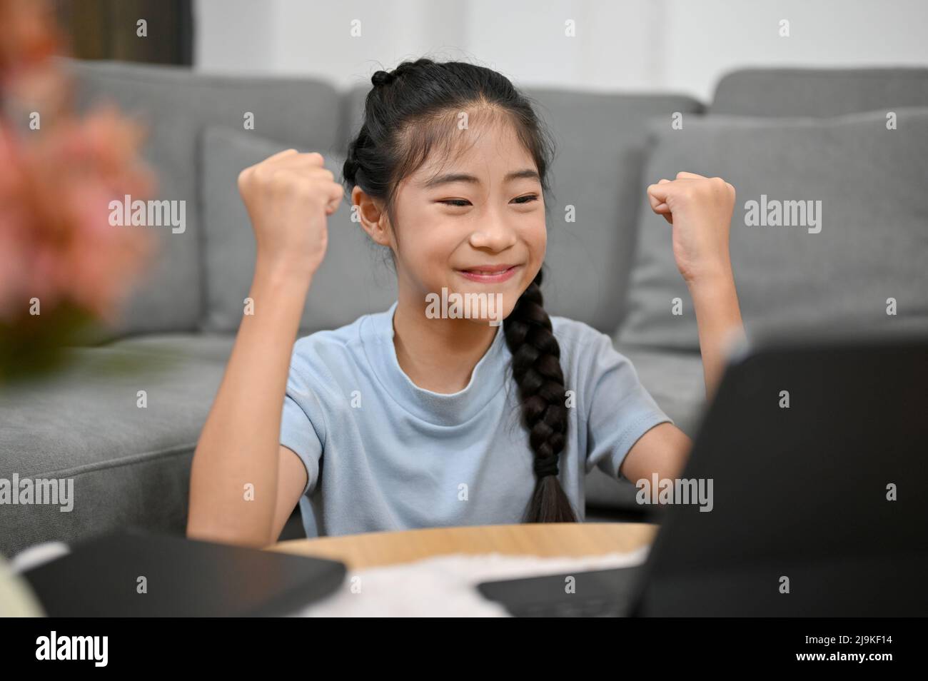 Happy Asian young girl enjoy watching online kids' cartoons or studying  online class with her classmates at home Stock Photo - Alamy