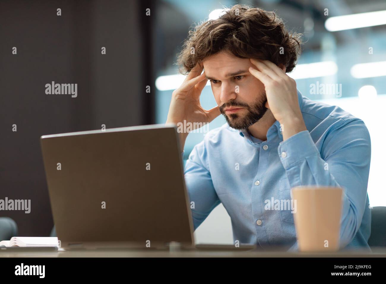 Sad business man grabbing head using pc Stock Photo - Alamy