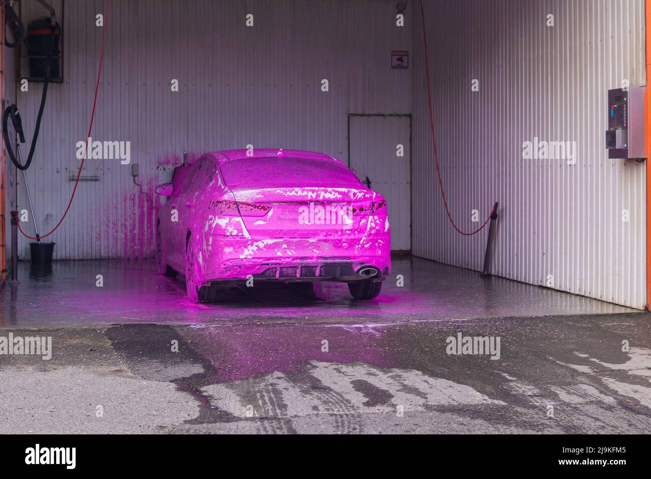 automobile at self service car wash covered with pink car shampoo Stock