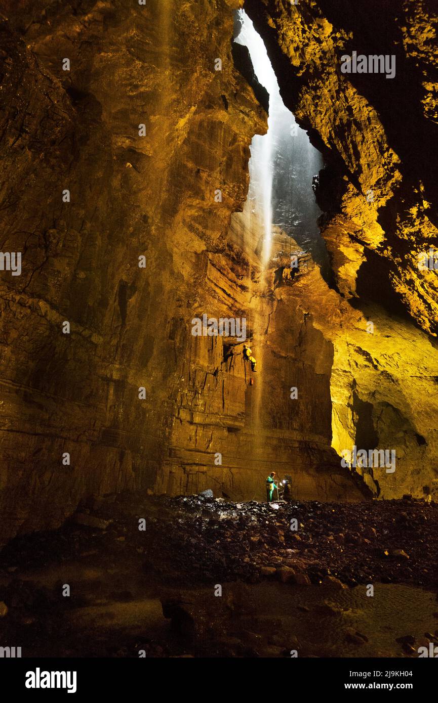 Inside the vast main cavern of Gaping Gill pothole, Ingleborough, Yorkshire Dales National Park, UK. A caver is seen descending on a rope. Stock Photo